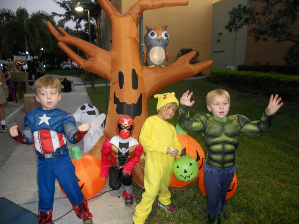 Kids dressed as Captain America, red Power Ranger, Pikachu and The Hulk stand in front of inflatable Halloween tree and inflatable jack-o-lanterns